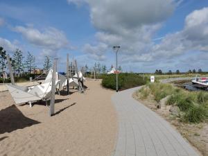 a walkway next to a beach with a boat at FeWo Westwind in Fehmarn