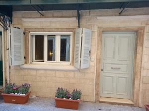 a building with two windows and two potted plants at Studio CASINELLA in Corfu