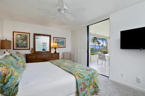 1 dormitorio con 1 cama y TV de pantalla plana en Polo Beach Club - CoralTree Residence Collection, en Wailea