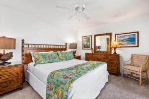 a bedroom with a bed and a chair and a mirror at Polo Beach Club - CoralTree Residence Collection in Wailea