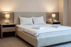 a bedroom with a large white bed with two lamps at Garni Hotel MB in Budva