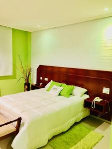 a bedroom with a large white bed with green walls at Motel Montecarlo in Lugo