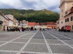 a square in a town with a mountain in the background at 4 Rooms Piata Sfatului in Braşov