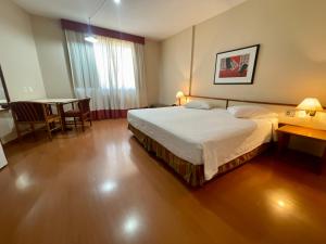 a hotel room with a bed and a table and a dining room at César Park Hotel in Juiz de Fora
