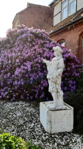 a statue in front of a bush of purple flowers at Gutshaus Nostalgie in Rätzlingen