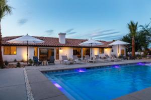 a house with a swimming pool with chairs and umbrellas at NEW Experience Base Camp An Exclusive Mountainside Desert Resort with 2 Pools in Palm Desert