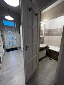 a bathroom with a door and a sink and a tub at Pázmány Rest Apartman in Budapest