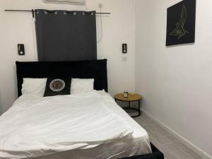 a white bed with a black headboard and a table at דירה גדולה יפיפיה קרובה לחוף הים in Tel Aviv