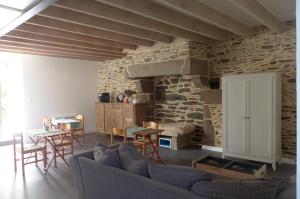 a living room with a couch and a stone wall at Maison d'hôtes KerCalow, Chambres d'hôtes in Pleine-Fougères