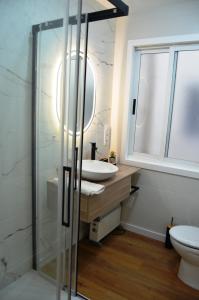 y baño con lavabo y ducha acristalada. en REGO DA RAÑA APARTMENTS, en Arzúa