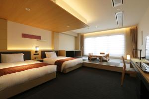 a hotel room with two beds and a window at Kanazawa Sainoniwa Hotel in Kanazawa