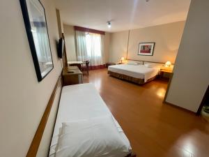 a hotel room with a bed and a desk with a table at César Park Hotel in Juiz de Fora