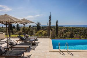 una villa con piscina y una persona sentada en una silla junto a en Luxury Villa Karmaniolos Fiskardo Kefalonia en Fiskardho