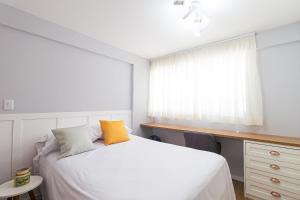 um quarto com uma cama branca e uma janela em Vossa Bossa Vitta Polopoli em São Paulo