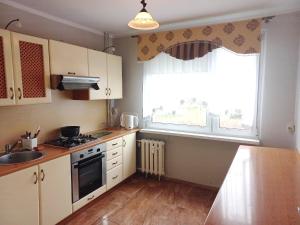 a kitchen with white cabinets and a sink and a window at Apartament M-3 in Częstochowa