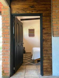 uma porta preta que leva a um quarto com uma cama em Habitación Rancho Las Moras em San Mateo Río Hondo