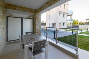a balcony with a wooden table and chairs and a large window at Momento Luxury Apartments walking distance from the beach in Nikiana