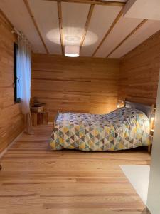 a bedroom with a bed in a room with wooden walls at L'écolodge de Laeti in Lunéville