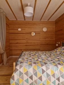 1 dormitorio con 1 cama con paredes de madera y techo en L'écolodge de Laeti, en Lunéville