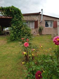 a garden with flowers in front of a house at Cabañas Don Fernando in Santa Rosa de Calamuchita