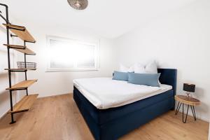 a bedroom with a blue and white bed and a window at Living797 in Albstadt
