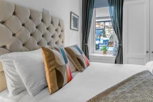 een slaapkamer met een wit bed met kussens en een raam bij Cheerful Stays - Jamson Pl 3 Bed Apartment in Edinburgh