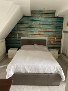 a bedroom with a white bed with a wooden wall at Cosy and Stylish 1BD-Limehouse in London