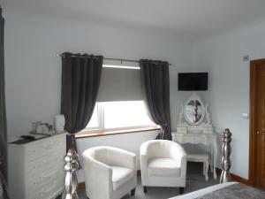 1 Schlafzimmer mit einem Fenster, 2 Stühlen und einer Kommode in der Unterkunft Gwynfryn Guest House in Pembrokeshire