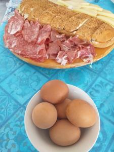 un panino e uova su un tavolo con una ciotola di cibo di B&B Solarium a Noto Marina