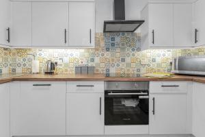 een keuken met witte kasten en een magnetron bij Cheerful Stays - Jamson Pl 3 Bed Apartment in Edinburgh