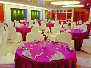 une salle de banquet avec des tables et des chaises violettes et blanches dans l'établissement DESHA TARC, à Kushtia