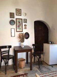 ein Esszimmer mit einem Tisch und Stühlen sowie einem Kühlschrank in der Unterkunft San Lorenzo Cottage - Παραδοσιακά Πέτρινα Δωμάτια in Agios Lavrentios