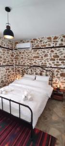 Cama en habitación con pared de piedra en San Lorenzo Cottage - Παραδοσιακά Πέτρινα Δωμάτια, en Agios Lavredios