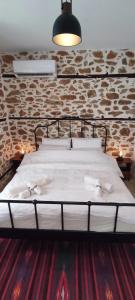 ein großes Bett in einem Zimmer mit einer Steinmauer in der Unterkunft San Lorenzo Cottage - Παραδοσιακά Πέτρινα Δωμάτια in Agios Lavrentios
