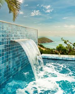 uma piscina de mergulho com cascata num resort em Buzios Mar Hotel em Búzios