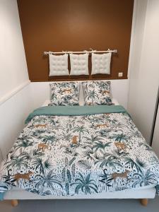 a bedroom with a bed with a tropical bedspread and pillows at Gite Duguesclin in La Flocellière