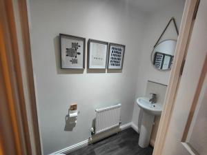 a white bathroom with a sink and a toilet at Shoreline Seaside Holiday Home Aberavon beach in Port Talbot