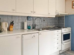 ウルリーセハムンにあるHoliday home ULRICEHAMN VIの白いキャビネットとシンク付きのキッチン