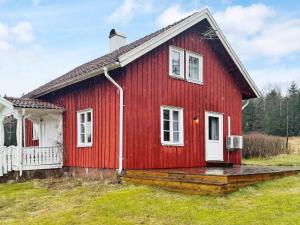 een rood huis met een witte deur en een veranda bij Holiday home ULRICEHAMN VI in Ulricehamn