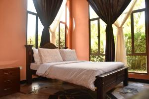 a bedroom with a bed in front of windows at Hotel Campestre Villa Los Duraznos in Paipa