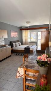 een woonkamer met een bed en een tafel met bloemen bij Artemis Hotel Apartments in Kavala