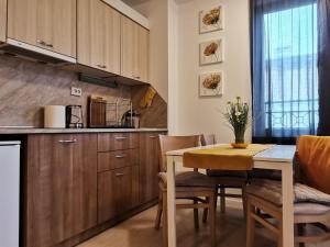 a kitchen with wooden cabinets and a table with chairs at Апартамент Orange в местност Каваци, Созопол in Sozopol