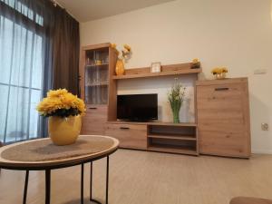 uma sala de estar com televisão e uma mesa com flores em Апартамент Orange в местност Каваци, Созопол em Sozopol