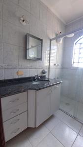 W białej łazience znajduje się umywalka i lustro. w obiekcie Quartos aconchegantes em Sobrado grande no meio do Brooklin w São Paulo