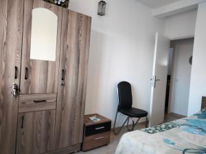 een slaapkamer met een houten deur en een stoel naast een bed bij Havre de Paix chez Lamine in El Harhoura