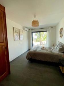 une chambre avec un lit et une grande fenêtre dans l'établissement Villa Camomille - Vue grandiose, à Saint-Pierre