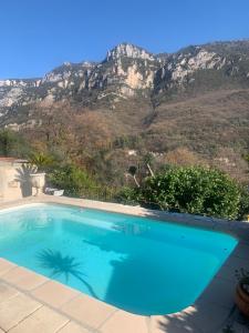 una piscina azul con montañas en el fondo en Charmante maison avec piscine en Gourdon