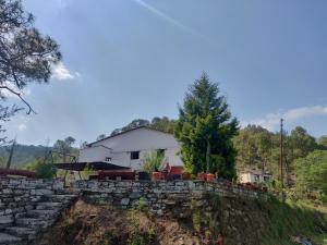 uma casa sentada em cima de uma parede de pedra em Kurmanchal Village by THE GHAUR em Almora