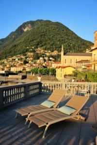 a couple of lounge chairs on a deck with a mountain at Ortensie & Oleandri al Lago - by MyHomeInComo in Argegno