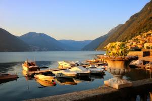 a bunch of boats are docked on a lake at Ortensie & Oleandri al Lago - by MyHomeInComo in Argegno